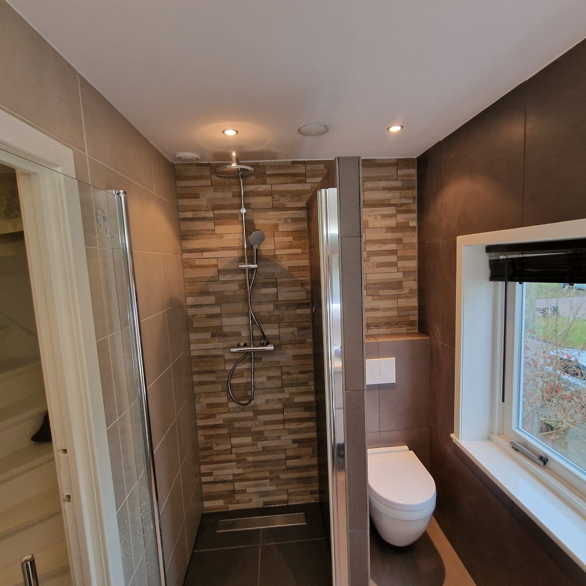 Afgewerkte badkamer met inloopdouche, houtlook wand en hangtoilet
